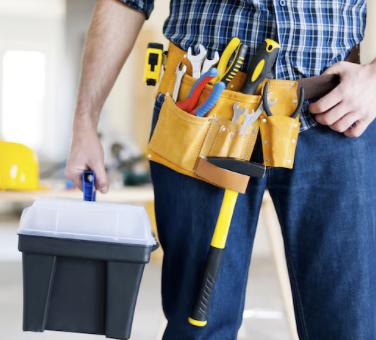 Hausmeister-Service Hausmeister mit Werkzeuggürtel und Werkzeugkiste in der Hand, bereit zur Arbeit.