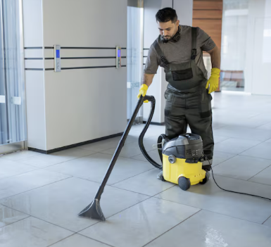 Bodenfliesen-Reinigung Ein Mann mit gelben Handschuhen reinigt Fliesen mit einem Bodenreinigungsgerät.