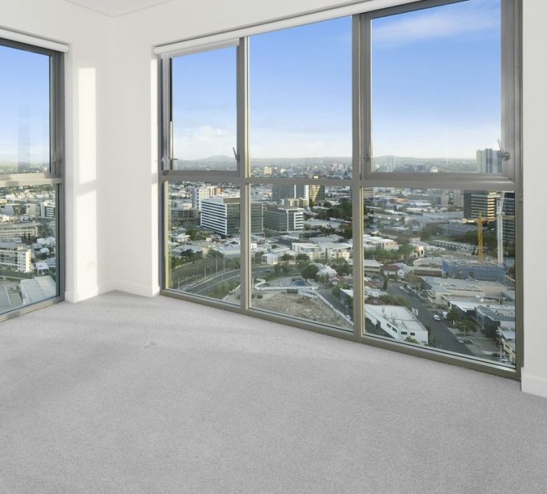 Fensterwand Heller Raum mit grauem Teppich und großer strahlend sauberer Fensterfront und Blick auf die Stadt.